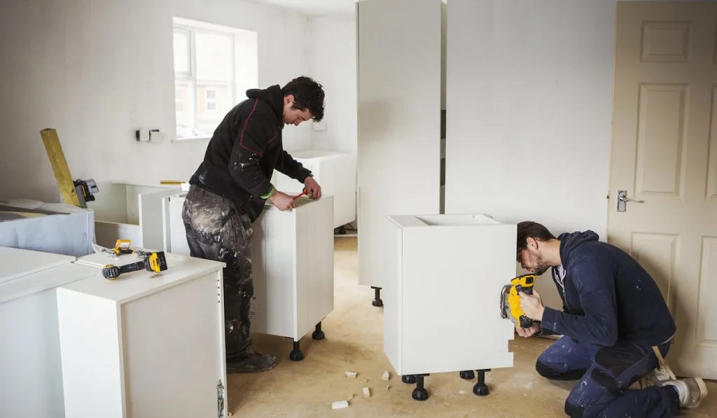 two male worker renovating kitchen cabinets