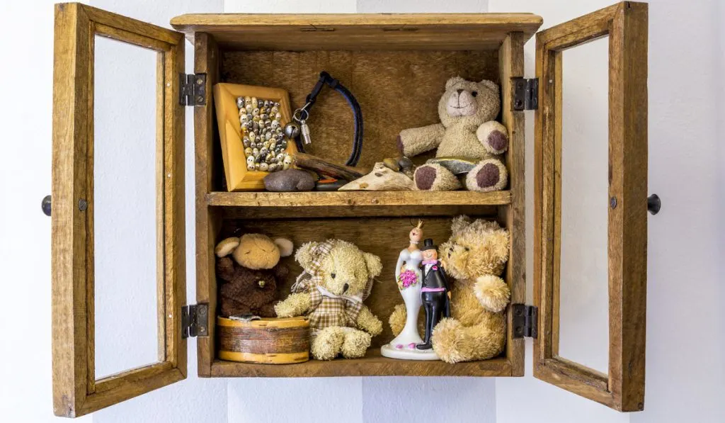 Rustic wood wall mounted display cabinet filled with small items and toys